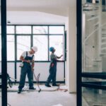 Two colleagues doing construction work together in an unfinished building.